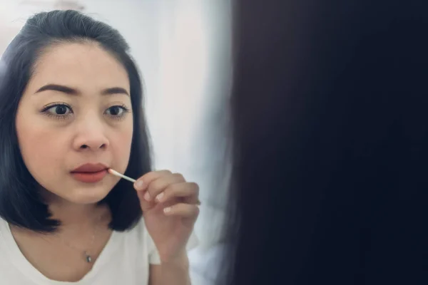 Женщина проверяет губы на зеркале в белой комнате. — стоковое фото