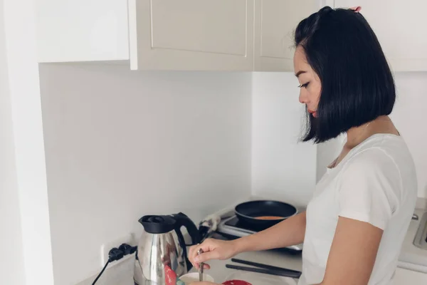 Woman is cooking simple breakfast in white cozy kitchen. — Stock Photo, Image