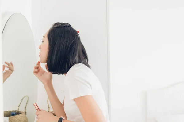 Женщина проверяет губы на зеркале в белой комнате. — стоковое фото