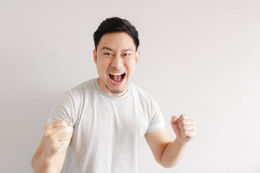 Adam heyecanlanıyor. Adam gri arka planda gri tişört giyiyor..