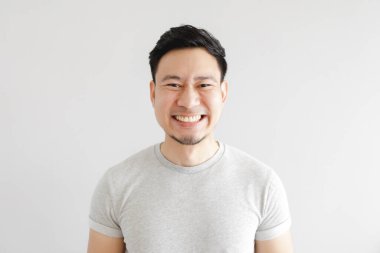 Mutlu bir adamın gülen yüzü gri tişört giyer ve gri arka planda.