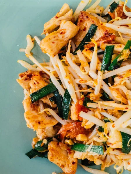 Geleneksel vejetaryen Tayland usulü kızartılmış tofu, pirinç eriştesi ve sebzelerden yapılmış basit yeşil seramik tabakta güzelce yerleştirilmiş..