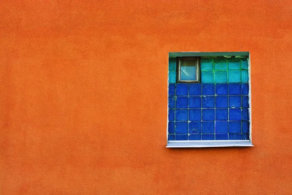 Fenêtre de carreaux verts et bleus dans un mur de plâtre orange — Photo
