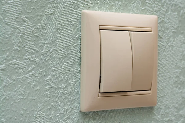 light switch, a white plastic mechanical switch mounted on a light blue wall. Copy space