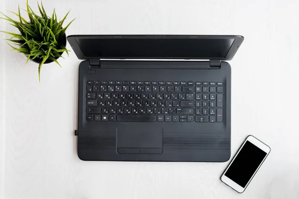 Laptop bilgisayarı, dizüstü bilgisayarı, telefonu ve bilgisayarı olan modern beyaz masa. Düz yatıyordu
