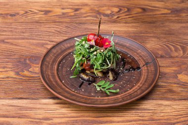 Patlıcanlı vejetaryen salatası ve ahşap arka planda bir tabakta roka.