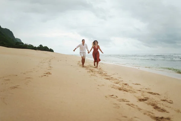 Młoda Piękna Para Biegnie Wzdłuż Piaszczystej Plaży Wybrzeżu Oceanu Trzymając — Zdjęcie stockowe