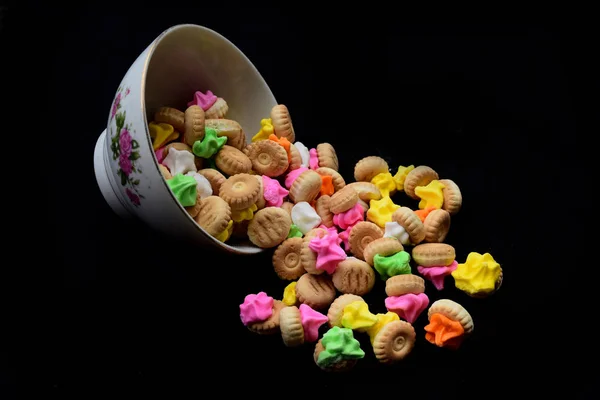 Endonezya renkli küçük ekmek atıştırmalıklar, bu aperatifler çok lezzetli ve tatlı tadı. boş bir siyah arka plan ile bir plaka üzerinde renkli küçük ekmek