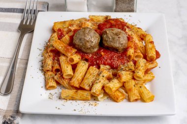 rigatoni üstü, köfte ve makarna sosuyla servis edilen bitkilerle dolu.
