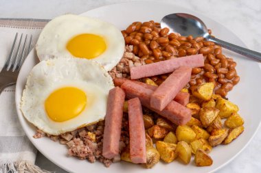 Kızarmış yumurta, sığır eti, fırında fasulye ve patates kızartmasıyla servis edilen patates kızartması.