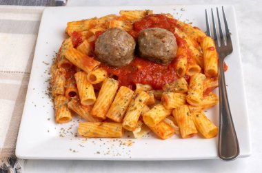rigatoni üstü, köfte ve makarna sosuyla servis edilen bitkilerle dolu.