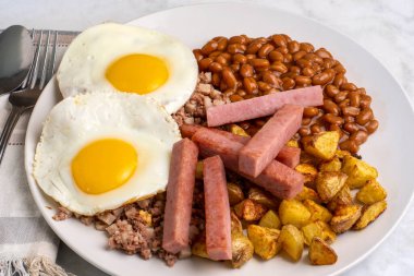 Kızarmış yumurta, sığır eti, fırında fasulye ve patates kızartmasıyla servis edilen patates kızartması.