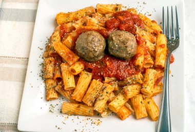 rigatoni üstü, köfte ve makarna sosuyla servis edilen bitkilerle dolu.