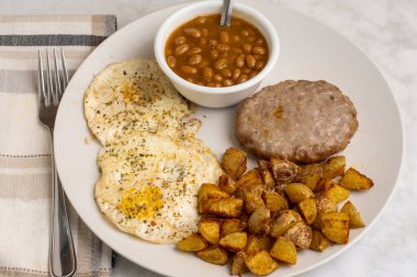 Biber ve maydanozlu yumurta sosisli börek, ev kızartması ve fırında fasulye ile servis edilir.