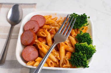  Peynirli makarna üstü, sosis ve brokoli ile servis ediliyor.