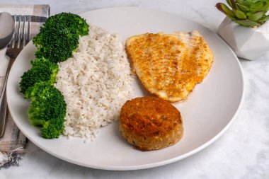  pilav ve brokoli ile servis edilen mezgit ve yengeç keki.