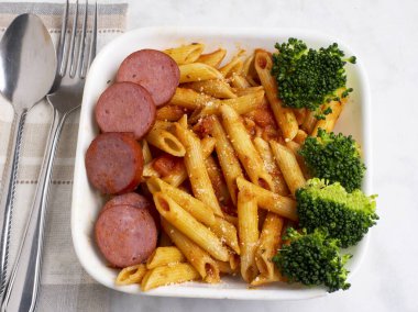  Peynirli makarna üstü, sosis ve brokoli ile servis ediliyor.