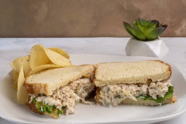 Patates cipsiyle servis edilen beyaz ekmeğin üzerine doğranmış turşulu tavuk salatası.