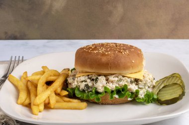 Tavuklu salata turşuyla karıştırılmış susamlı çörek ve yanında patates kızartması.