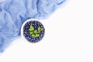 Bir kase ve beyaz arka plan üzerinde izole ışık mavi tül kumaş taze yaban Yaban mersini. Üstten görünüm.
