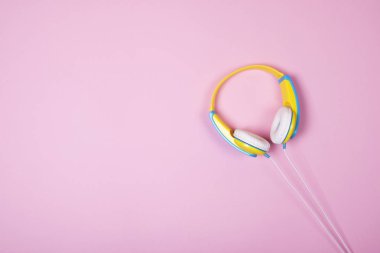 Pembe arka plan kopya alanı ile mavi ve sarı kulaklıktan.