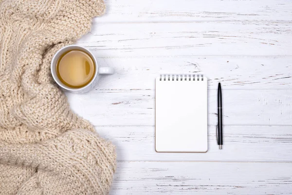 Σύνθεση του φλιτζάνι τσάι, καρό μπεζ, σημειωματάριο και στυλό πάνω σε λευκό φόντο ξύλινη. — Φωτογραφία Αρχείου
