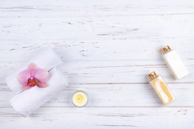 Farklı spa, güzellik ve sağlıklı yaşam ürünleri: krem, deniz tuzu, havlu, kopya alanı ile orkide çiçek ve mum ile dekore.  