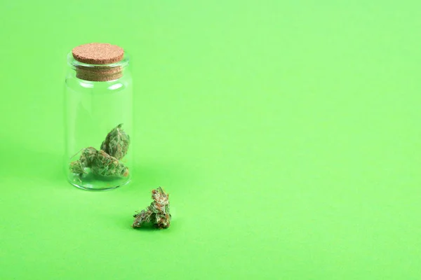 绿色背景玻璃瓶中的干医用大麻芽. — 图库照片