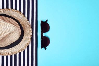 Çizgili giysiler, güneş gözlüğü ve turkuaz arka plan üzerinde hasır şapka. Üst te. Düz yatıyordu.