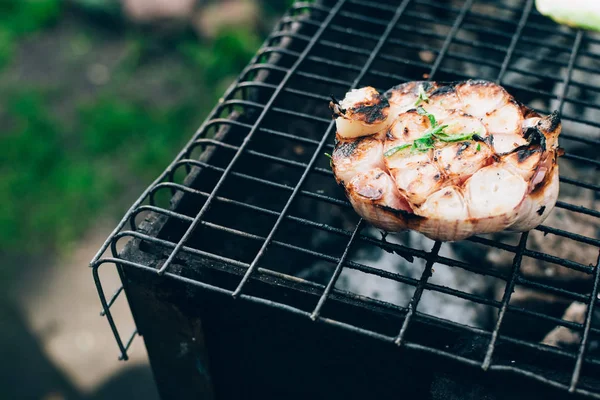 Ail rôti coupé en deux avec des épices sur un barbecue . — Photo