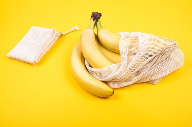 Sarı arka plan üzerinde plastik ücretsiz geri dönüşümlü tekstil torbası muz Demet. Eko kavramı. Sıfır atık yaşam tarzı.