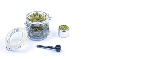Fresh green buds or flowers of cannabis marijuana in glass jar and grinded weed in box and smoking pipe. Banner. — Stock Photo, Image