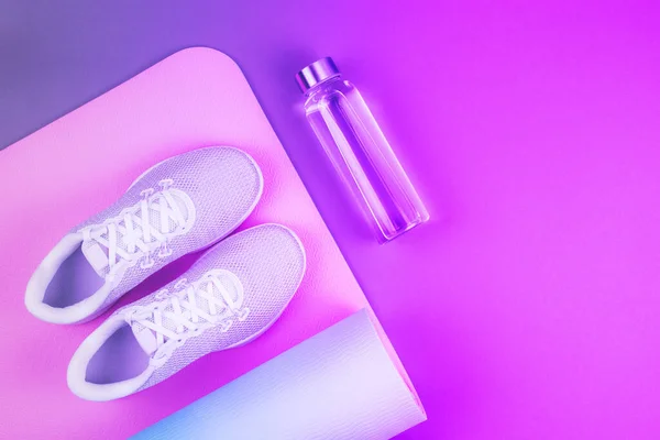 Neon mor ve pembe renkli spor ayakkabıları, yoga minderi, metin için yeri olan yeniden kullanılabilir eko cam su şişesi. Yoga, pilates ya da fitness pratiği. Kilo verme ve spor konsepti.