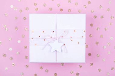 Pastel pembe hediye kutusunun en üst görüntüsü ve arka planda altın konfetiyle süslenmiş fotokopi alanı olan yıldız. Düz yatıyordu. Bayram festivali konsepti.