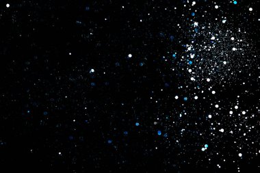 Siyah kozmik soyut arkaplan üzerinde mavi parıltılar veya parıltılar.