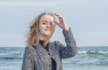 Kız denize yakın yürür. Bahar yüzünde yer aldı! Bir portre resmi bir gülümseme ve iyi bir ruh hali bu. Fotoğraf Odessa, Ukrayna, Karadeniz üzerinde Mart 2019 çekilmişti.