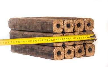 Yakıt briketleri beyaz bir arka plan üzerinde sıralar halinde katlanmış. Ahşap briketler yangın çıkarmak için kullanılan çevre dostu bir yakıt kaynağıdır. Kuru talaş preslenmesi ile yapılır.