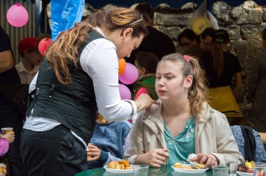 Çocuklar ve ebeveynler için açık etkinlik. Yetişkinler ve çocuklar dinlenir, tatlı yer, müzik dinler ve oyun oynarlar. Gülümseyen insanların portreleri.  