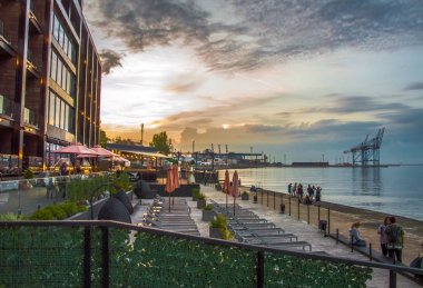 Deniz de gün batımı. Güzel binalar ve liman.