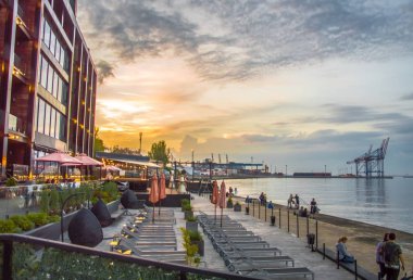 Deniz de gün batımı. Güzel binalar ve liman.