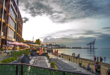 Deniz de gün batımı. Güzel binalar ve liman.