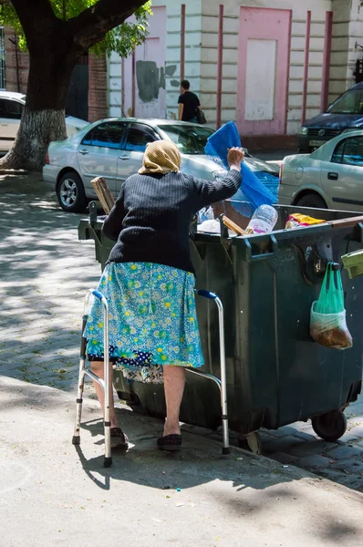 An old woman throws out trash. — Stock Photo, Image