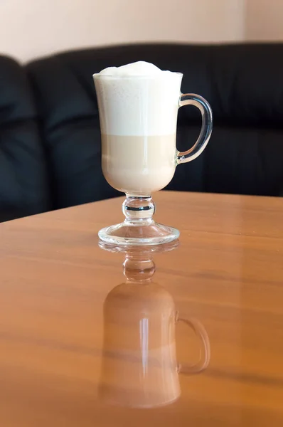 Una taza de café de pie sobre una mesa de oficina de madera . —  Fotos de Stock