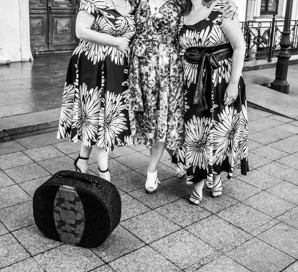 Three women in identical dresses and black bag. — Stock Photo, Image