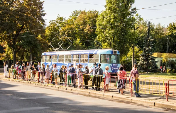 Insanlar otobüs durağında duran ve tramvay bekliyor. Kamu