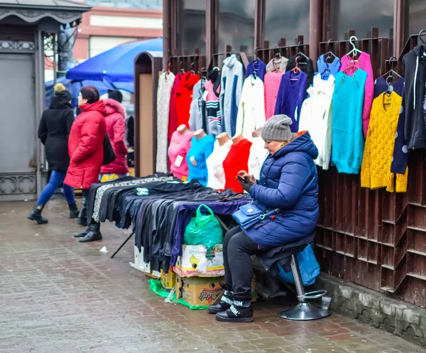 Mujer comerciando en un mercado callejero mirando un gadget . —  Fotos de Stock