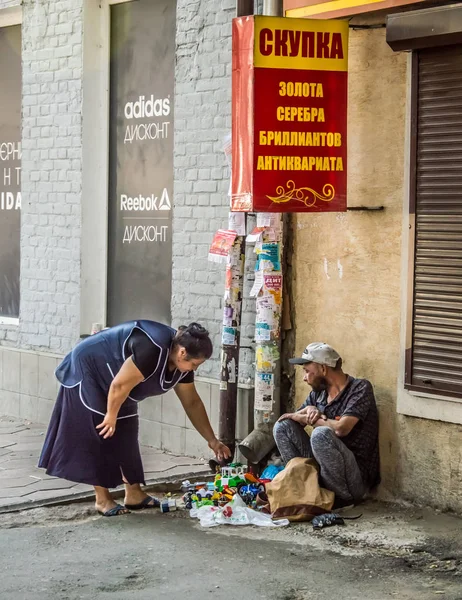 Un mendigo vende viejos juguetes de plástico en la calle . —  Fotos de Stock