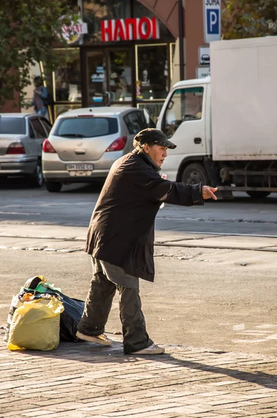 Un mendigo con bolsas en la calle . — Foto de Stock