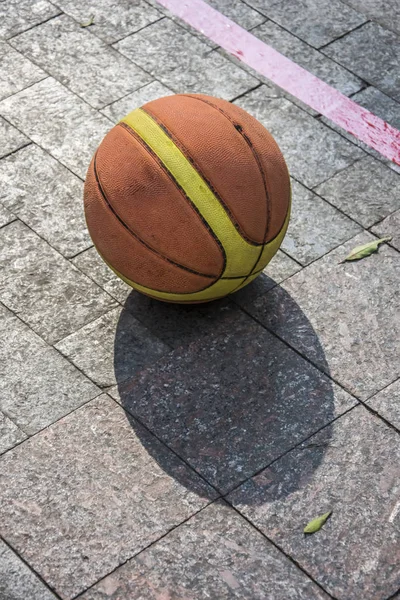 Basketbal liggend op een straat tegel. — Stockfoto