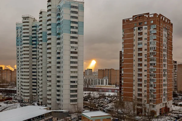 An unusual phenomenon in the sky over the residential area of a big city. The sun\'s rays make their way through the clouds to the high-rise buildings in a residential area.